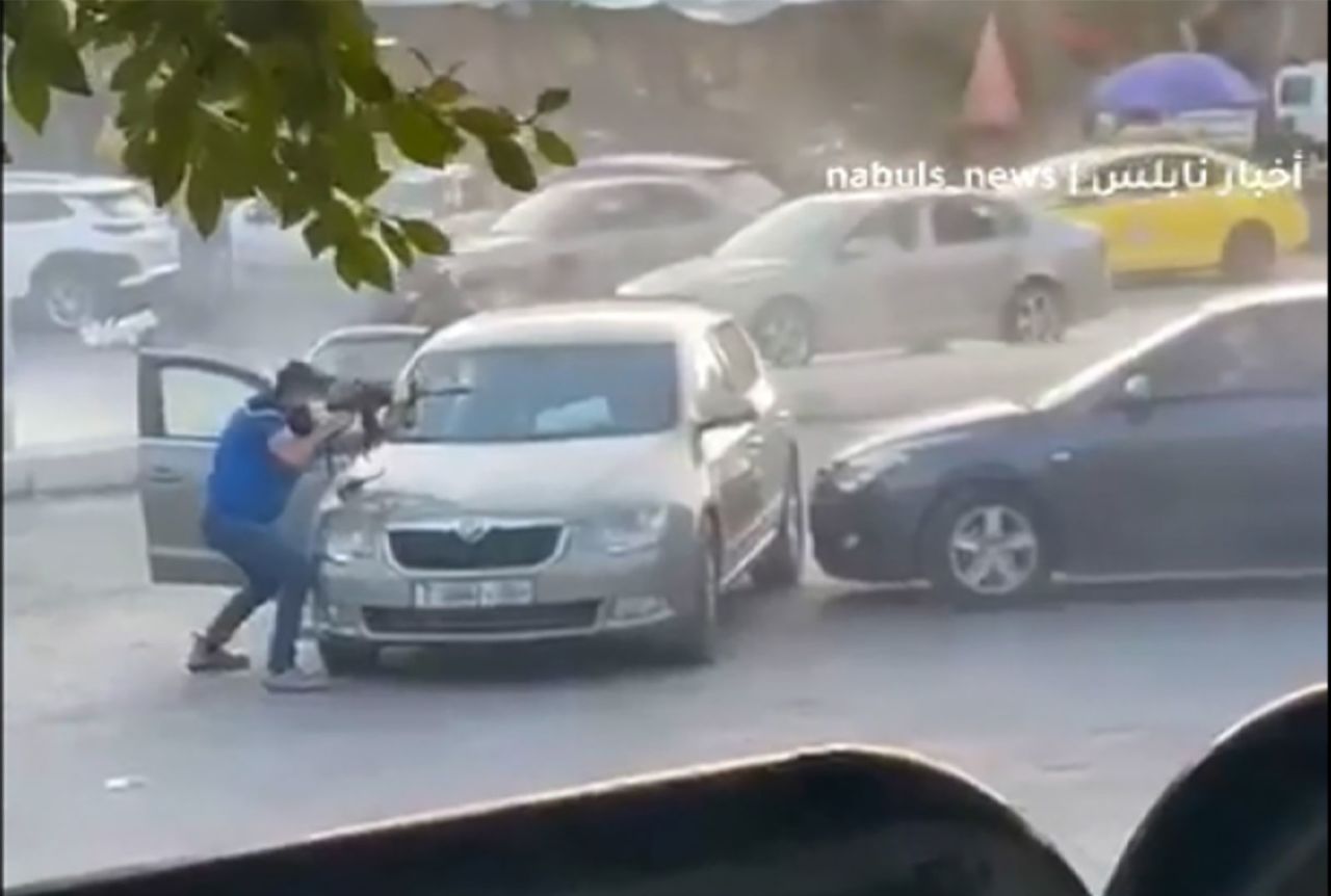 A video obtained by CNN shows at least four men standing behind a car while holding assault rifles and shooting at a second car across from them.