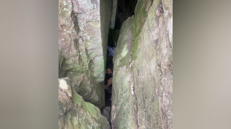 A woman trapped in a 3-meter crevice between two boulders is seen after slipping while trying to retrieve her phone.