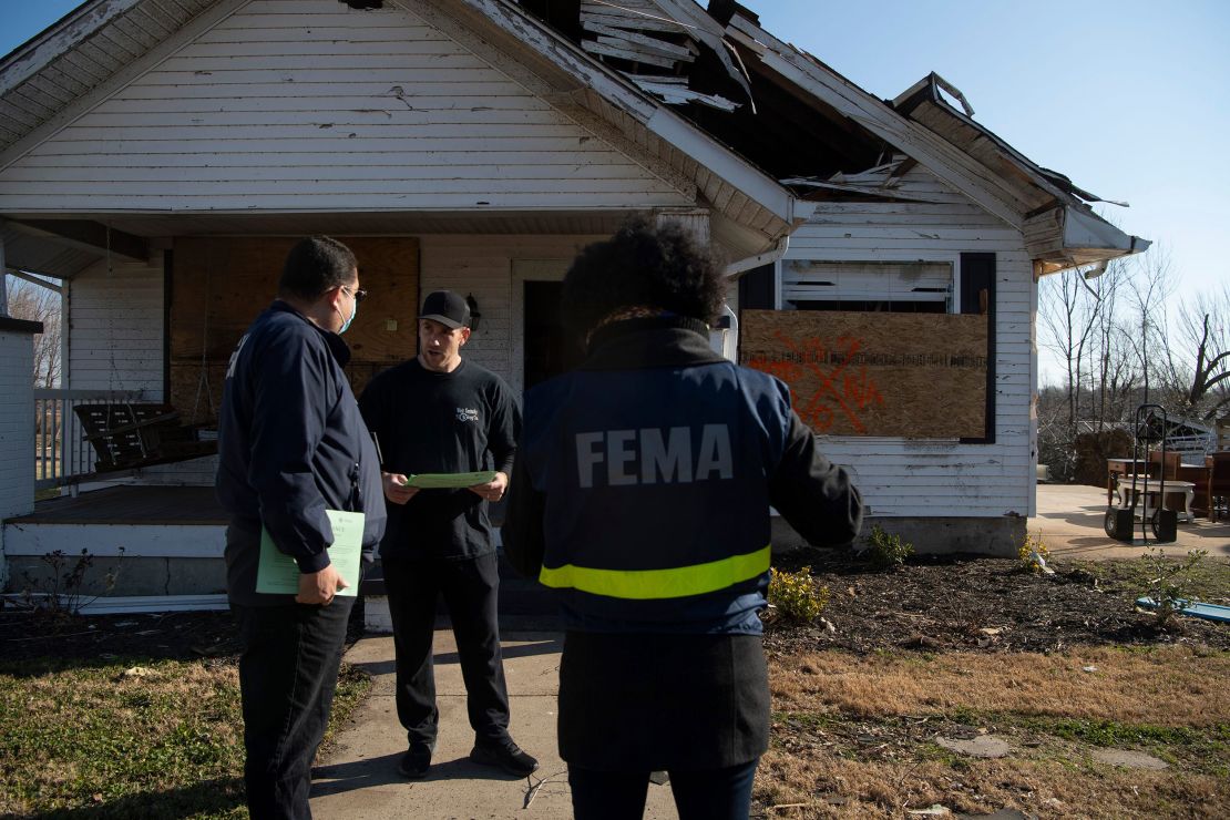 FEMA Disaster Survivor Assistance Specialists Marc Ocasio, left, and Lynisha Warren, right, speak to Trace Burlingame in Mayfield, Kentucky, in December 2021. The team was going door-to-door to meet survivors of a tornado that tore through the area earlier that month.