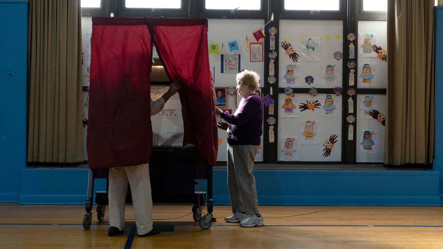 A poll worker sets up the voting machine for a man to cast his ballot at a school in Paramus, New Jersey, on November 8, 2022.