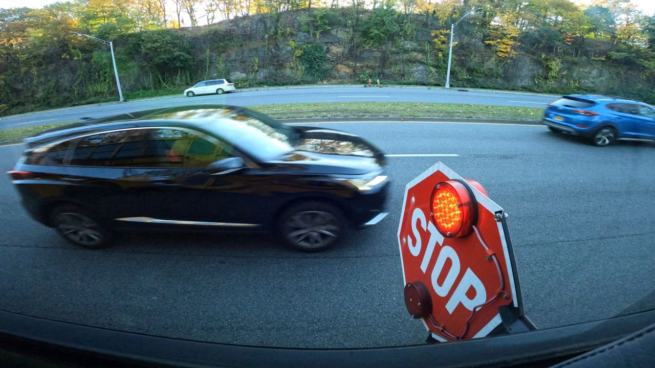 Two cars drive past a school bus' flashing stop sign on Central Park Ave. in Yonkers. The First Student bus was taking students to the Casimir Pulaski School Weds. morning Nov. 8, 2023.