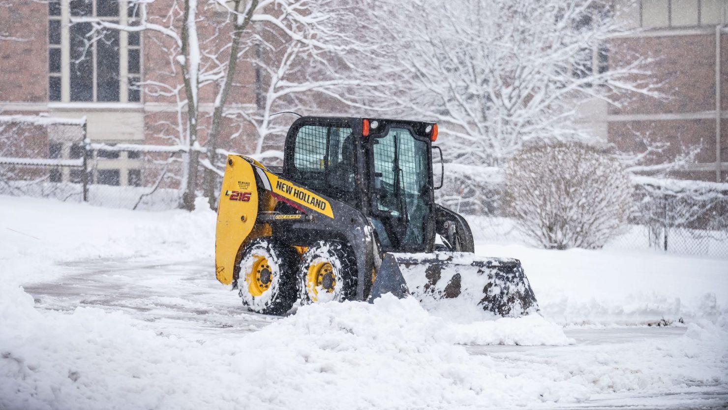 A skid steer clears a driveway in Pewaukee on Friday morning after a spring storm dumped snow across the area.
