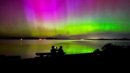 Marshall Falcon, left, photographs the northern lights as he and Angie Avitia watch the celestial display from Perkins Peninsula Park, west of Eugene, Oregon, on Friday, May 10.