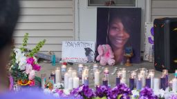 Guests at the memorial service held one month after the death of Sonya Massey in Springfield, Illinois, look at candles, flowers and photos displayed on the front porch of Massey's home.