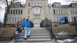 A parent brings their child into Trowbridge Street School of Great Lakes Studies in Milwaukee on Friday, Feb. 28, 2025. The Milwaukee Health Department has ordered the school to temporarily close starting Monday after finding “unsafe lead dust levels” within the building.