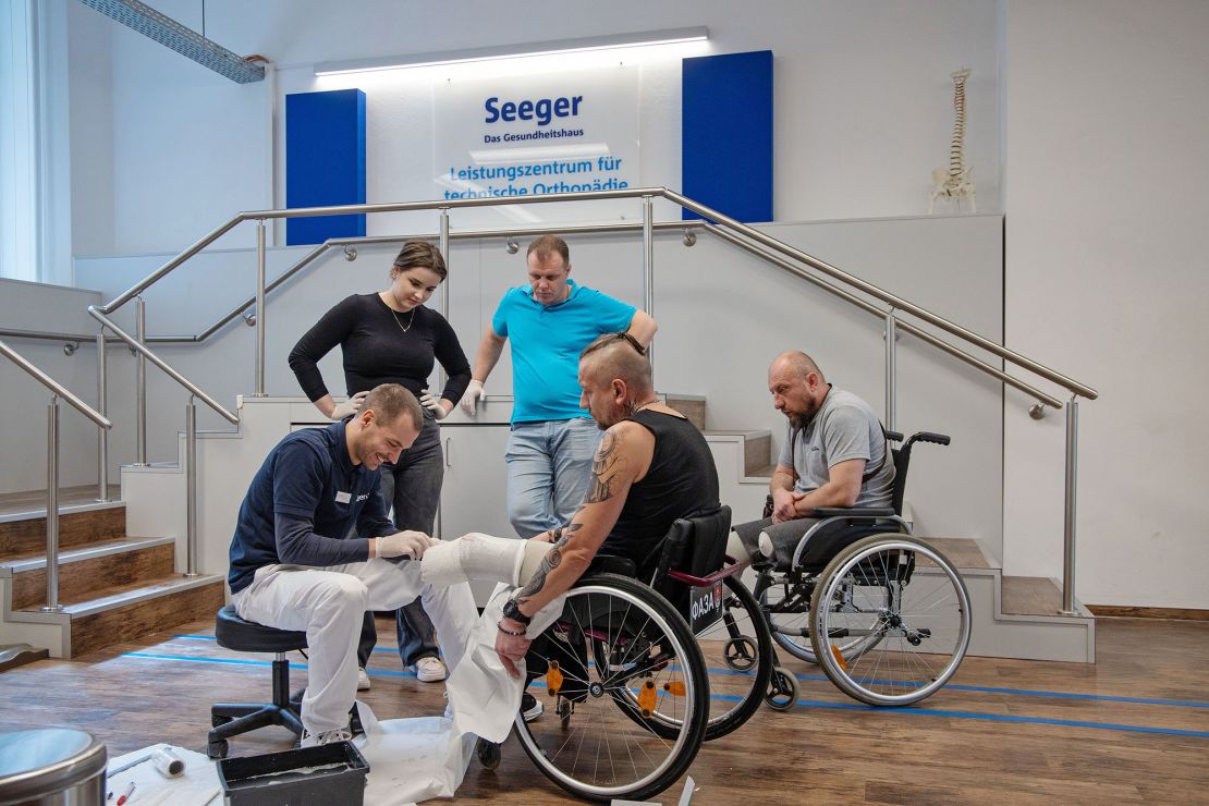 Orthopedic technicians work with Vitaliy Sayko-Kazakov, seated center, and Pavlo Kushnirov, right, who are among the first of 60 injured Ukrainian soldiers who will receive specialist treatment in Berlin.