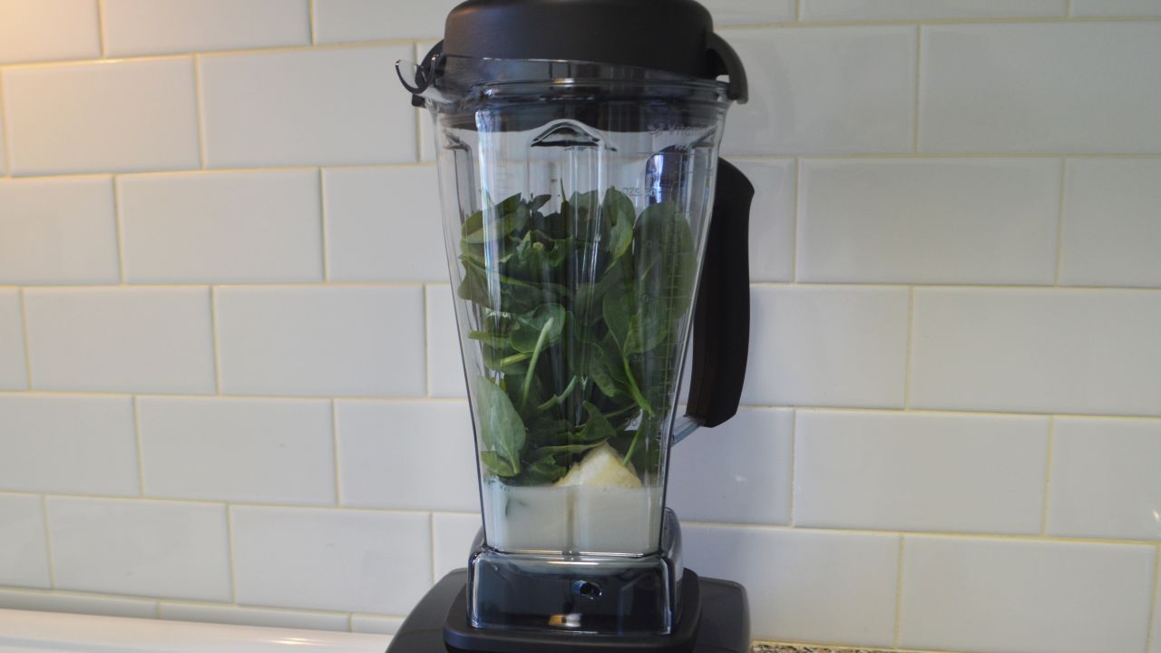 Vitamix with green smoothie supplies inside