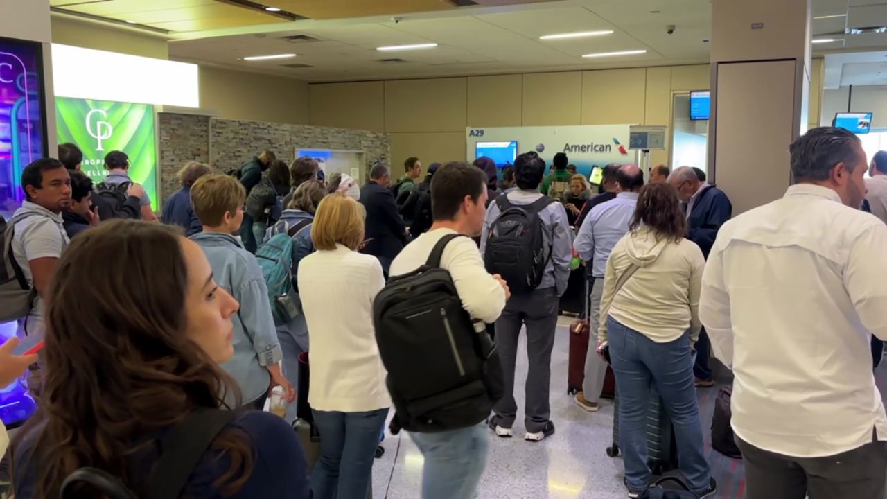 People gather near an American Airlines desk on Friday, September 19, as planes are delayed at Dallas-Fort Worth International Airport due to a reported telecommunication outage.