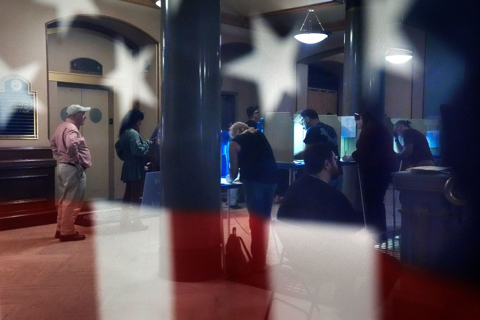 Voters are reflected in a window Friday as they mark their ballots at City Hall in Providence, Rhode Island.