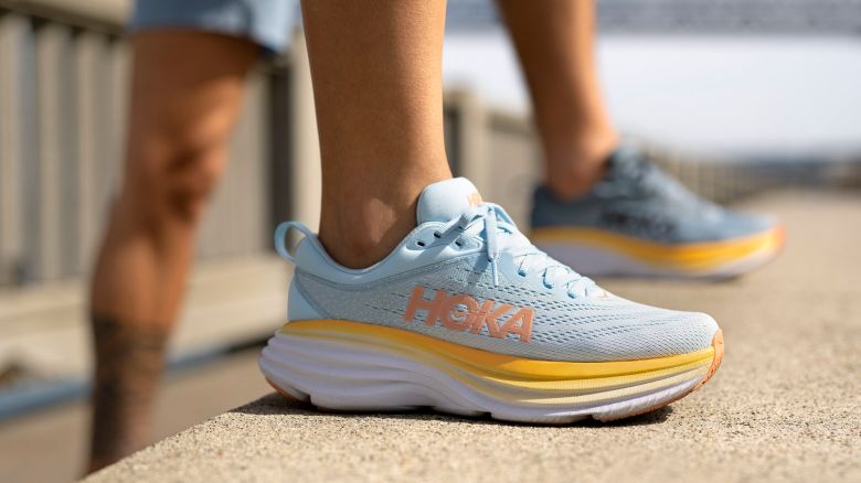 Person standing with Hoka shoe on the foreground.