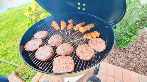 Burgers and skewers on a Weber kettle grill.