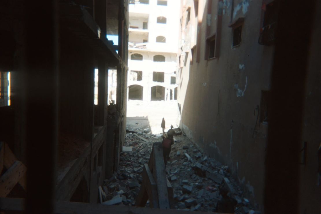 A photograph shows two soldiers urging a Palestinian forward in a scene of devastation in northern Gaza.