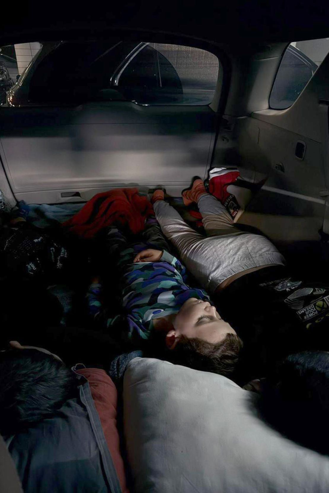 Khrystyna Reshetnik's sons sleep in a car as the family shelter during a Russian aerial attack on Kyiv on June 9, 2025.