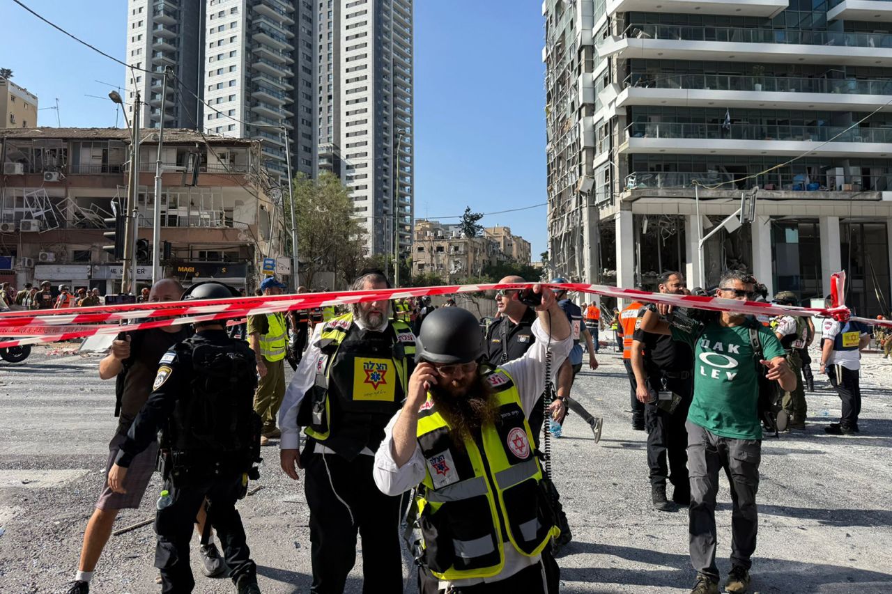 Kurtarma görevlileri ve askeri personel, Ramat Gan'daki füze saldırısının yerini inceliyor.