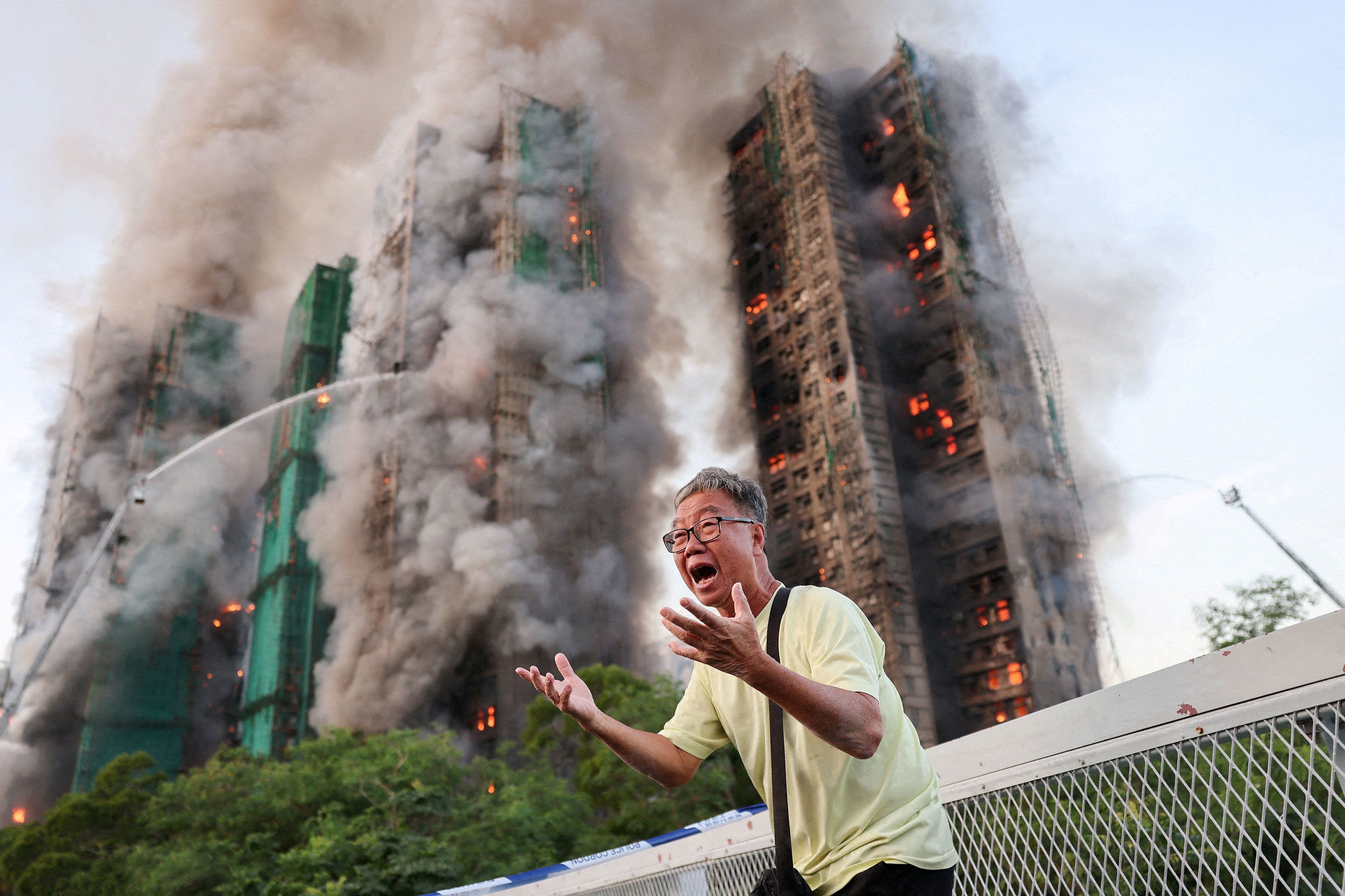 A man reacts as firefighters battle a massive blaze that had spread across multiple high-rise apartment buildings in a Hong Kong housing complex on Wednesday, November 26. The man said his wife was trapped inside.