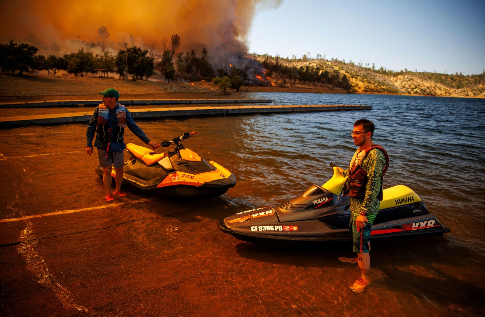 People on jet skis watch as the Thompson Fire burns in Oroville, California, on Tuesday, July 2. Because of the wildfire, thousands of people have been <a href="index.php?page=&url=https%3A%2F%2Fwww.cnn.com%2F2024%2F07%2F03%2Fus%2Fthompson-fire-california-heat-wave%2Findex.html">ordered to evacuate </a>in Northern California.
