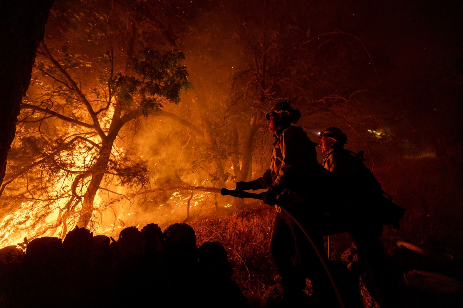 Firefighters establish a defense perimeter around a house that was threatened by the Bridge Fire in Wrightwood, California, on Tuesday, September 10. Flames exploded overnight in Southern California, where at least three large wildfires — the Bridge, Line and Airport fires — <a >have forced evacuations and strained local resources</a>.