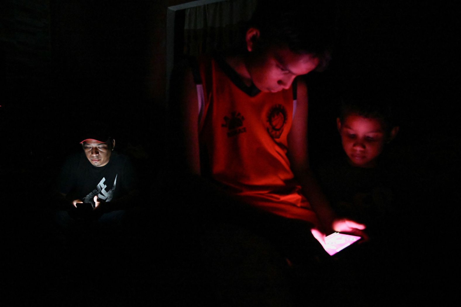 Darwin Medina and his sons Johan and Damir check their phones during a power outage in Guayaquil, Ecuador, on Monday, September 23.