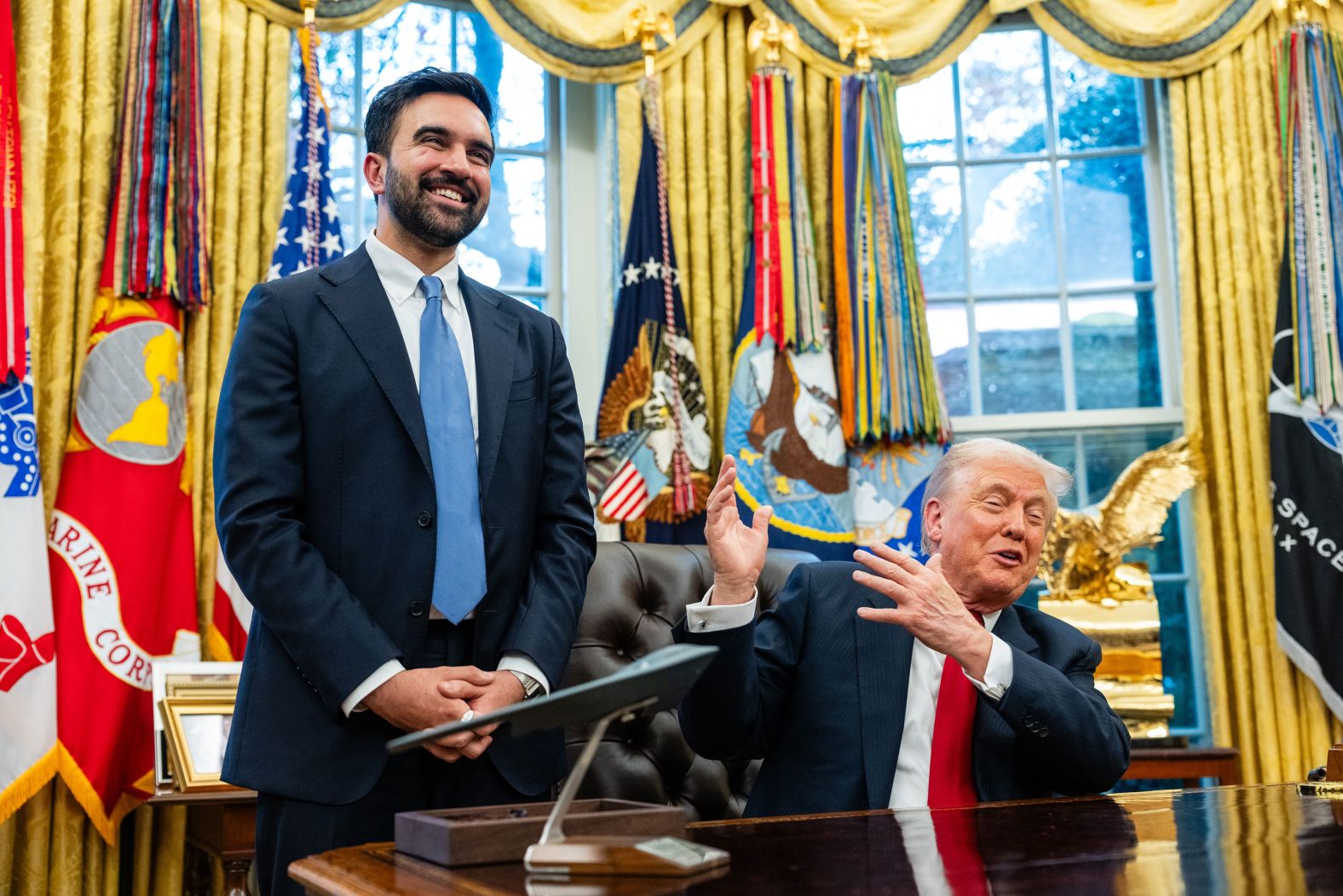 US President Donald Trump gestures to New York Mayor-elect Zohran Mamdani as they speak to reporters in the White House Oval Office on Friday, November 21. Trump heaped praise on Mamdani, suggesting he and the man he often falsely referred to as a “communist” actually had quite a bit in common. It was a surprisingly positive ending to a<a  href="/mt/?noimg=&dark=on&url=https%3a%2f%2fwww.cnn.com%2f2025%2f11%2f23%2fpolitics%2ftrump-mamdani-meeting-immigration-details-discussion">high-stakes meeting</a> between two diametrically opposed politicians who have spent several months trading barbs.
