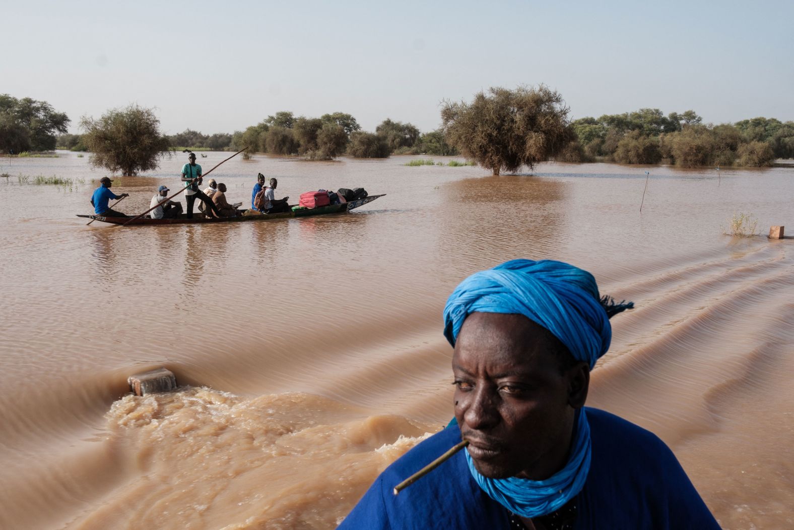 People carry their possessions on a boat as they navigate floodwaters that affected a main road in Odobere, Senegal, on Tuesday, October 22. Flooding caused by heavy rain has affected tens of thousands of people in the Senegal River Basin.