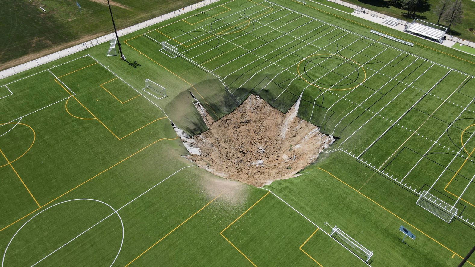 This 100-foot-wide sinkhole, photographed on Thursday, June 27, <a href="index.php?page=&url=https%3A%2F%2Fwww.cnn.com%2F2024%2F06%2F27%2Fus%2Fvideo%2Fmassive-sinkhole-soccer-field-alton-illinois-digvid">opened up on a turf soccer field</a> after a mine underground collapsed in Alton, Illinois.