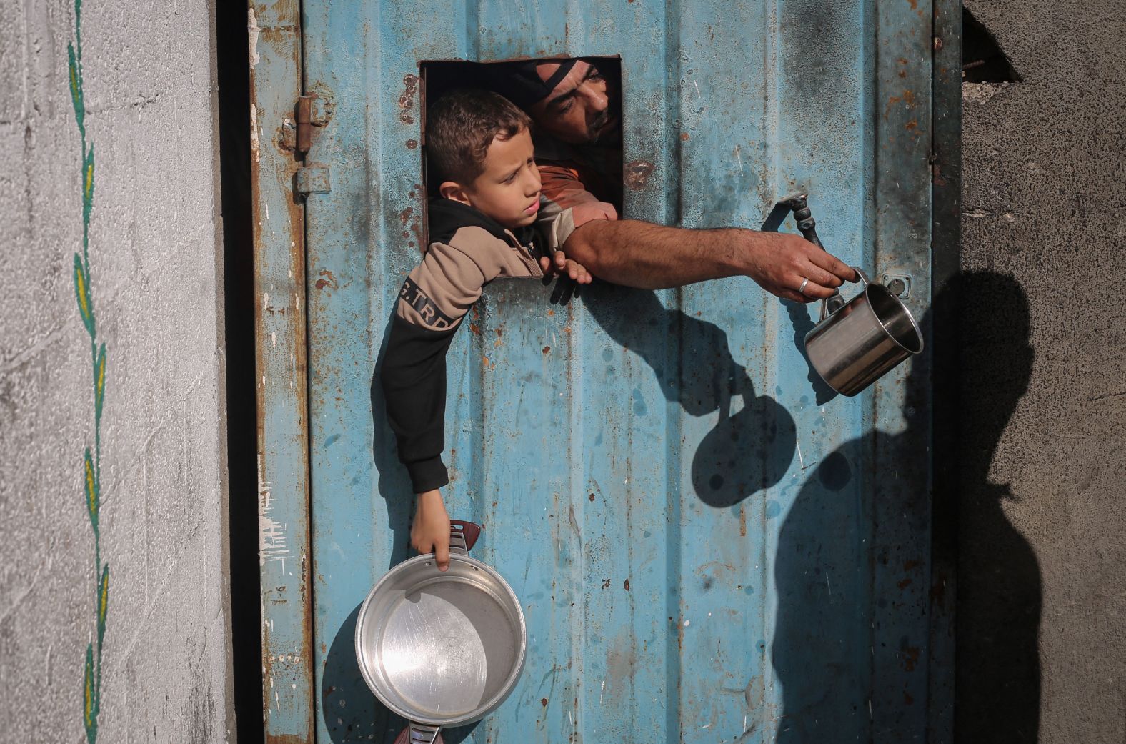 Displaced Palestinians wait for food at a shelter in Nuseirat, Gaza, on Sunday, November 23.