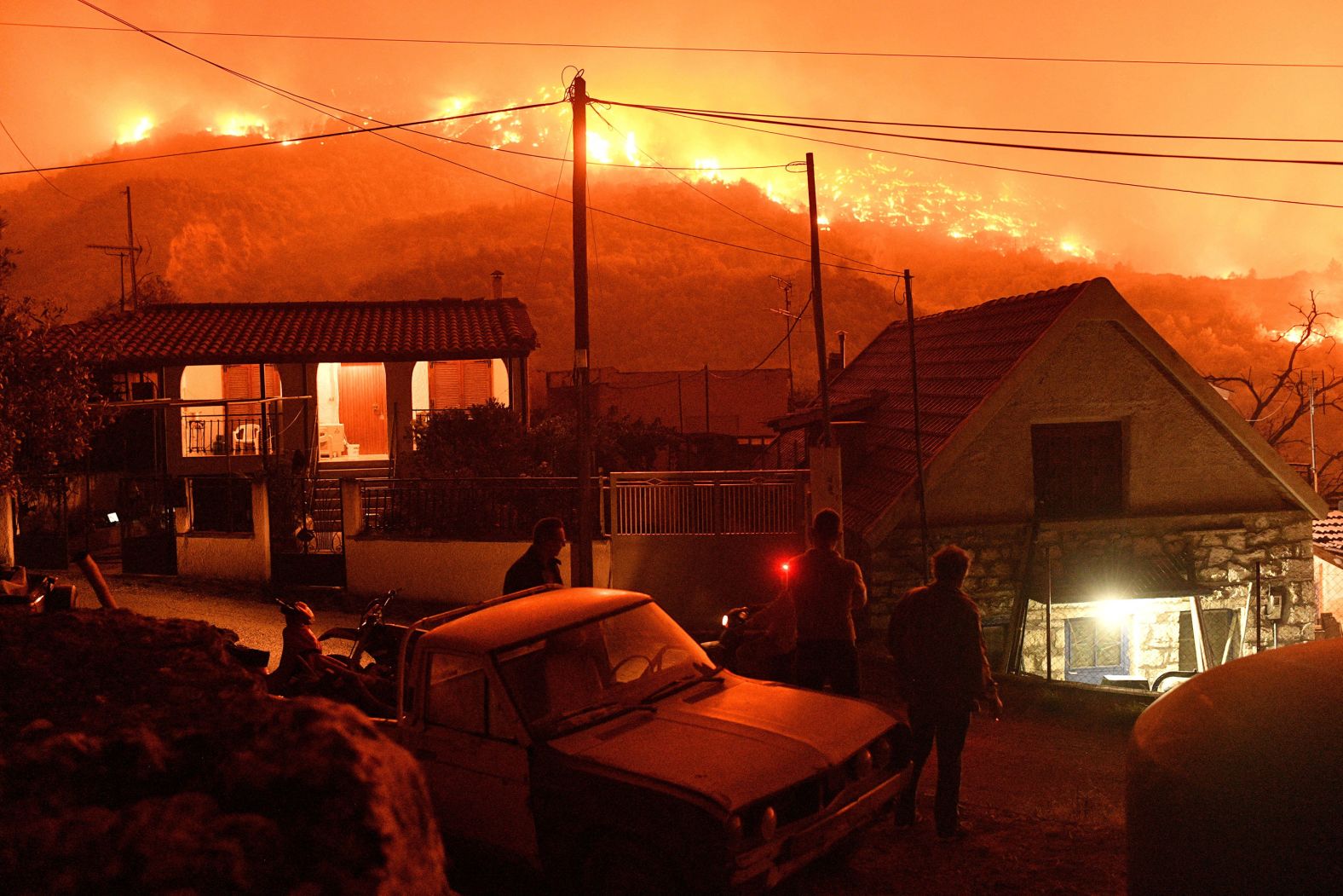 People near the Greek village of Kallithea watch flames rise from a nearby wildfire on Sunday, September 29.