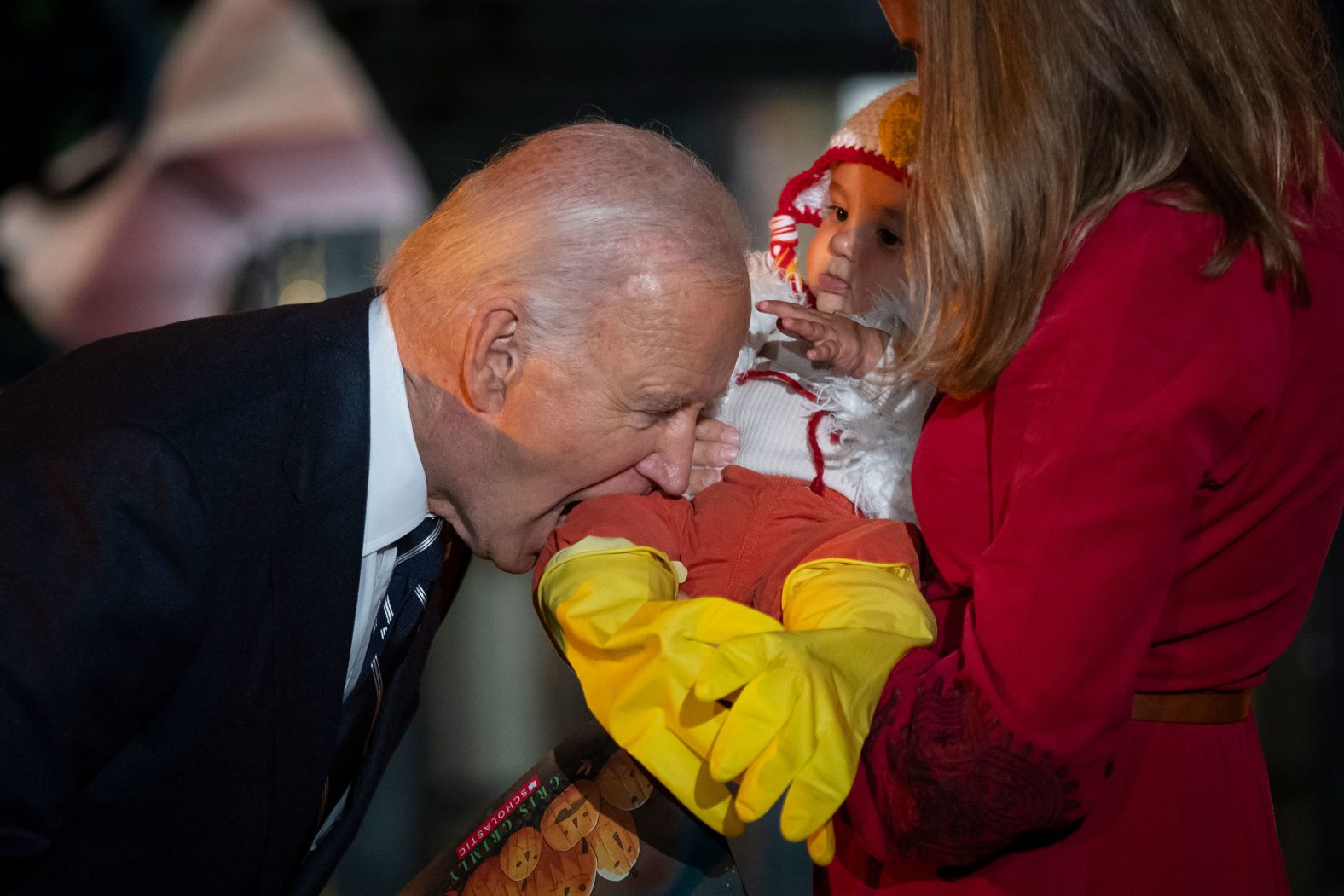 President Joe Biden jokingly bites the leg of a baby during a trick-or-treating event hosted by the White House on Wednesday, October 30.