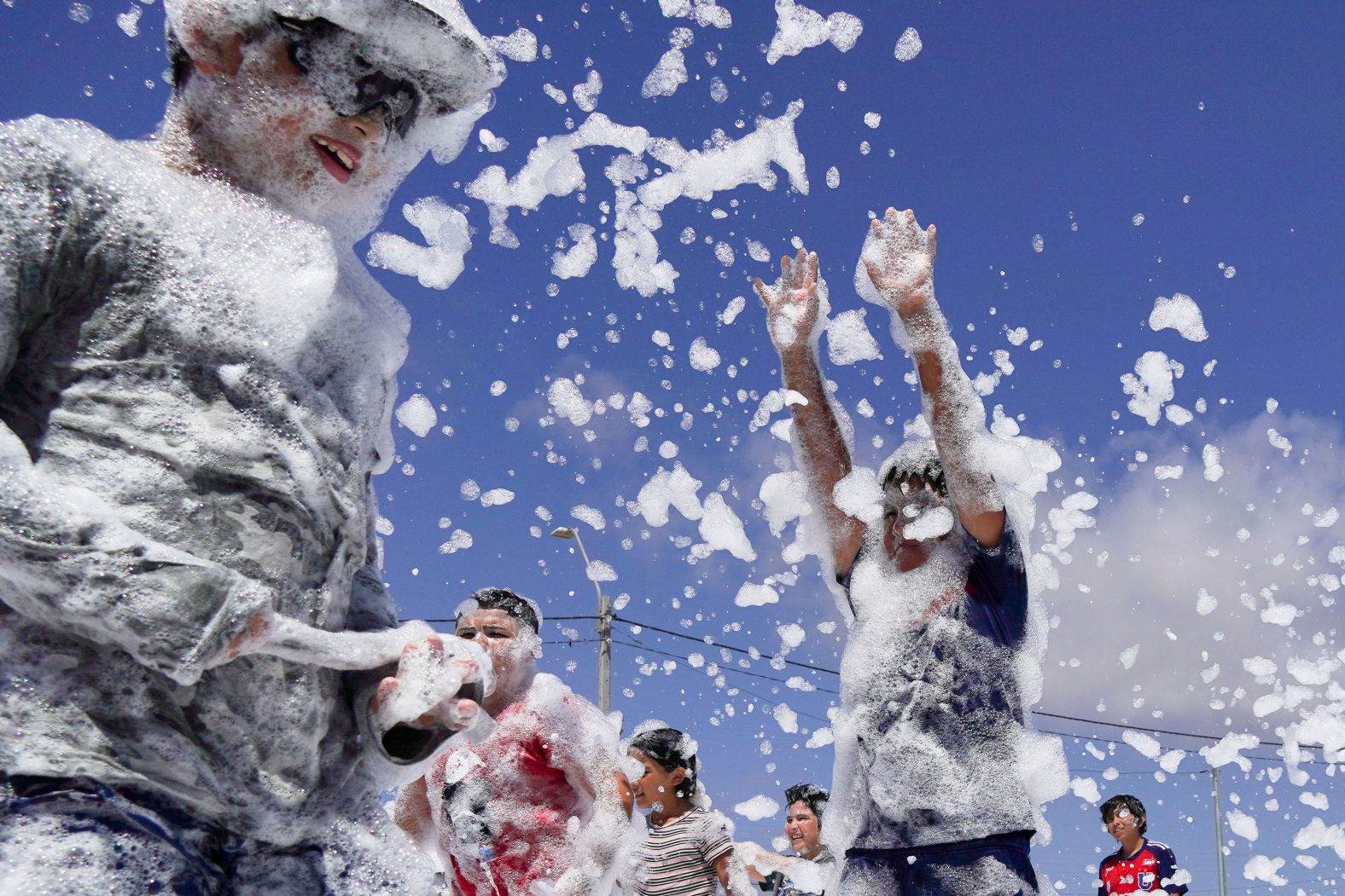 Children in Tongoy, Chile, play on a court blanketed with soap foam on Thursday, January 25.