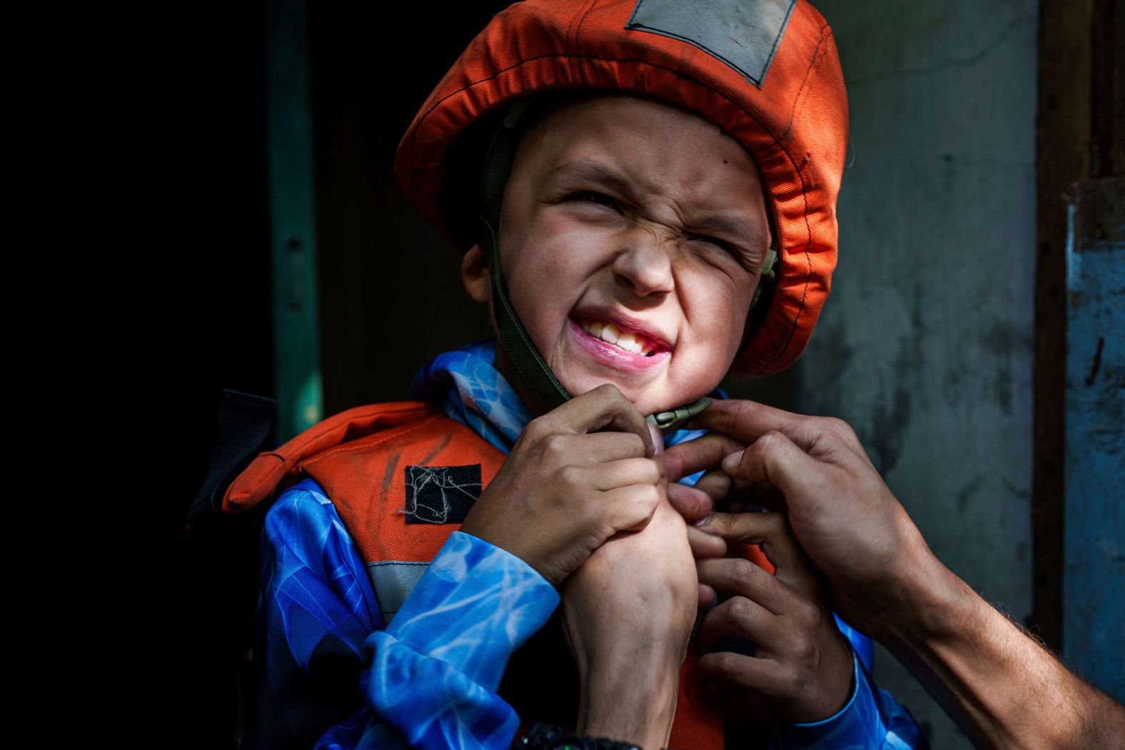 A rescue worker places a helmet on 9-year-old Bohdan Scherbyna as he and his family are evacuated from Selydove, Ukraine, on Tuesday, August 20.