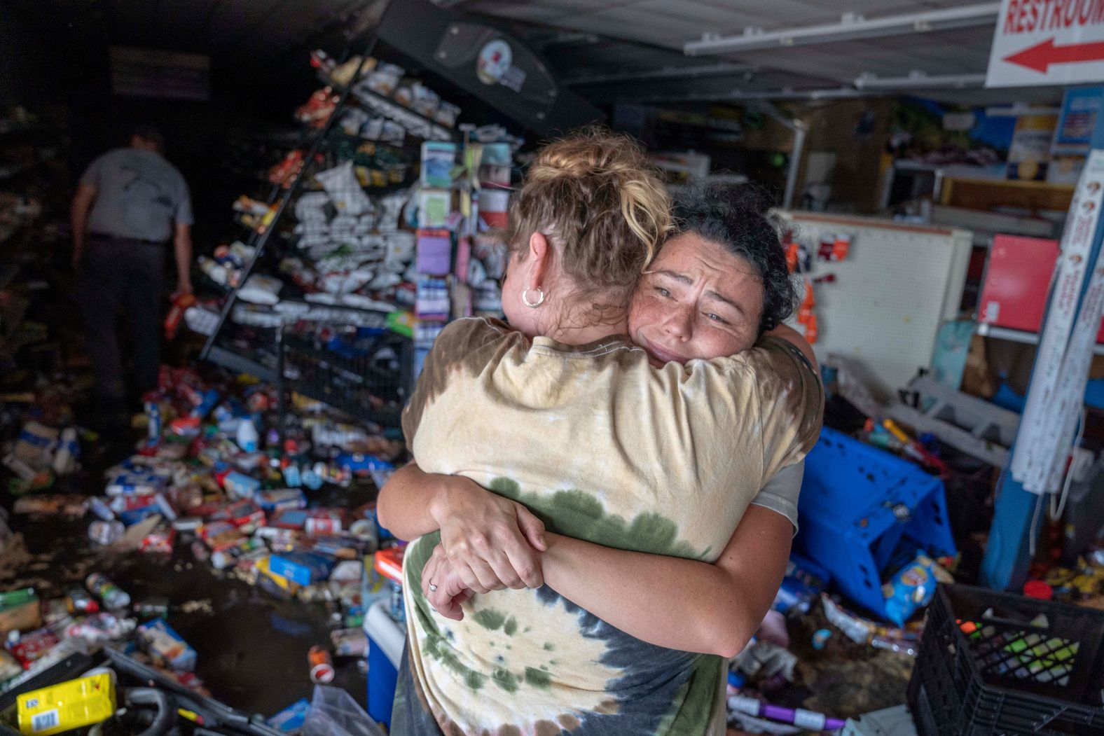 Cassandra Randall, right, is hugged by Jessica Downey inside a Maddie's Market after Hurricane Helene flooded the grocery store in Steinhatchee, Florida, on Friday, September 27. Randall's mother-in-law manages the store.