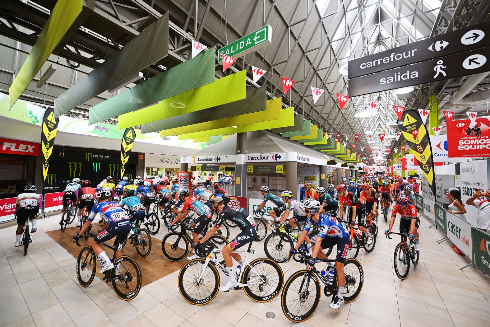 Cyclists ride through a shopping mall in Jerez de la Frontera, Spain, prior to the sixth stage of the Tour of Spain, on Thursday, August 22.