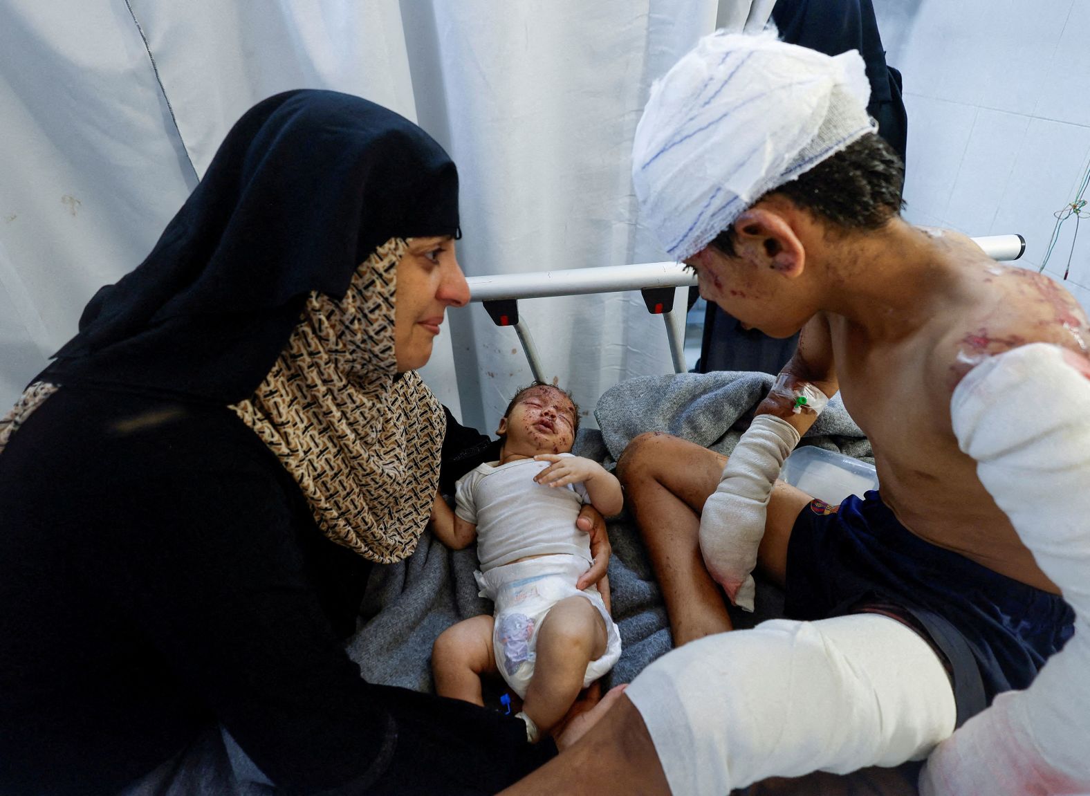 Palestinian child Tareq Qamar, who according to Reuters was hurt in an Israeli strike that killed his mother, is carried by his aunt as his injured brother Mohammed rests on a bed at the Nasser hospital in Khan Younis, Gaza, on Tuesday, July 2.