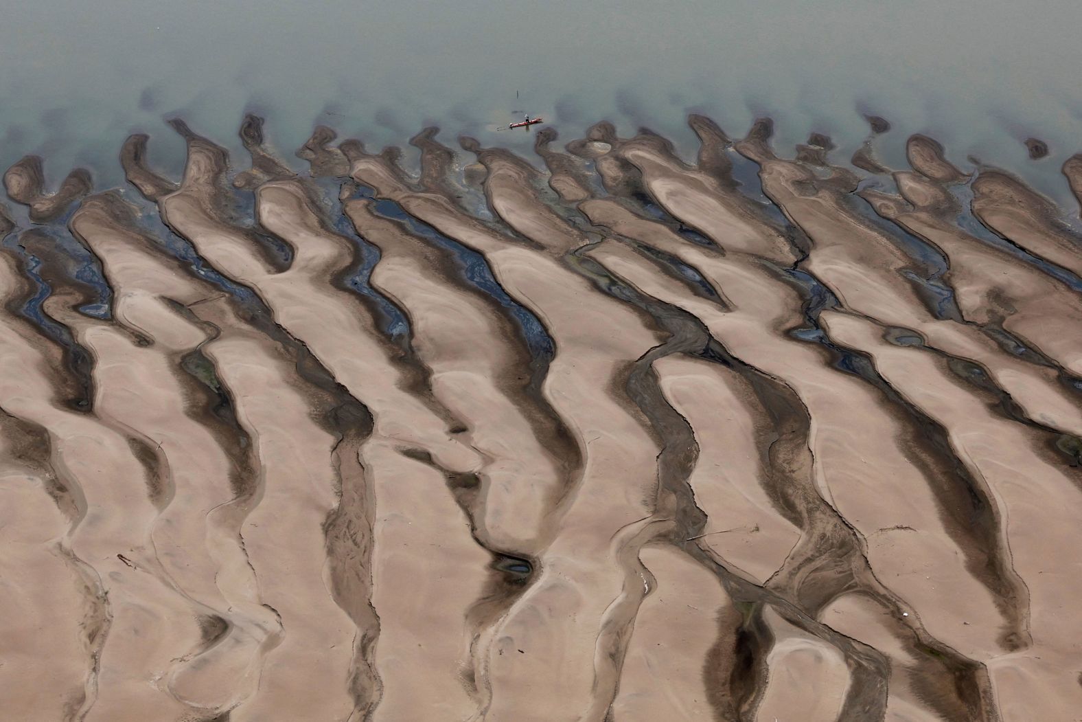 A man rides a boat in front of sandbanks at the Solim?es River, one of the largest tributaries of the Amazon River, during a Greenpeace flyover to inspect drought conditions near Tefé, Brazil, on Tuesday, September 17.