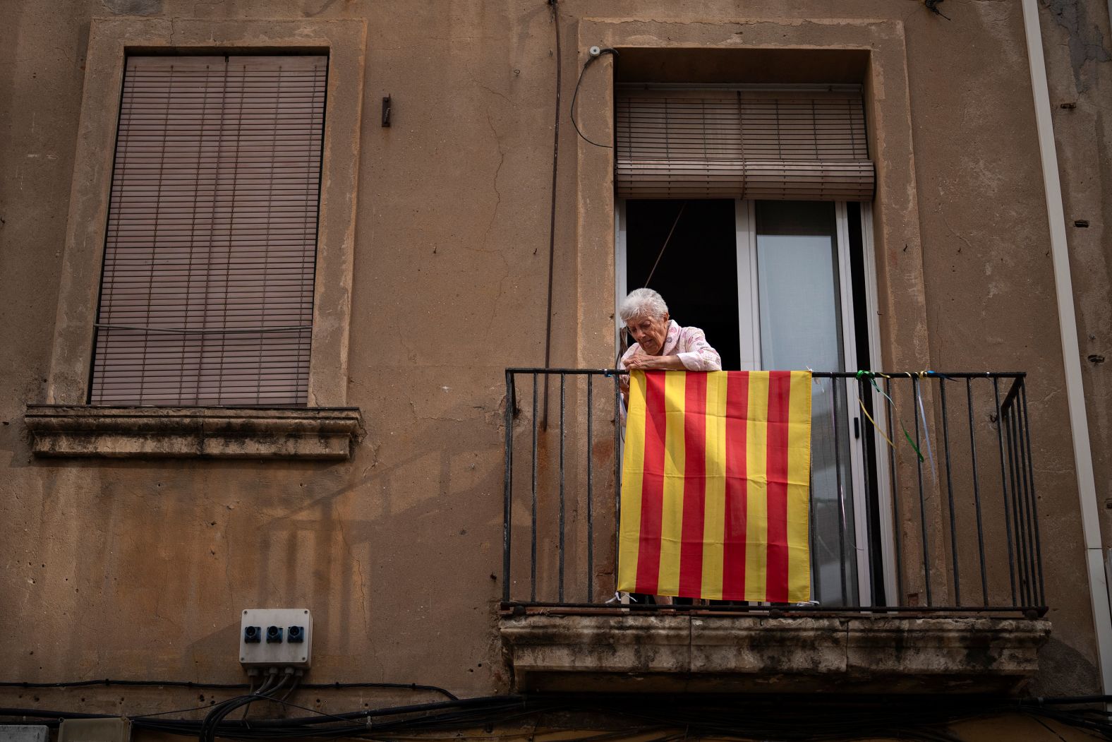 A woman puts a Catalonian flag on her balcony in Barcelona, Spain, during the National Day of Catalonia on Wednesday, September 11.