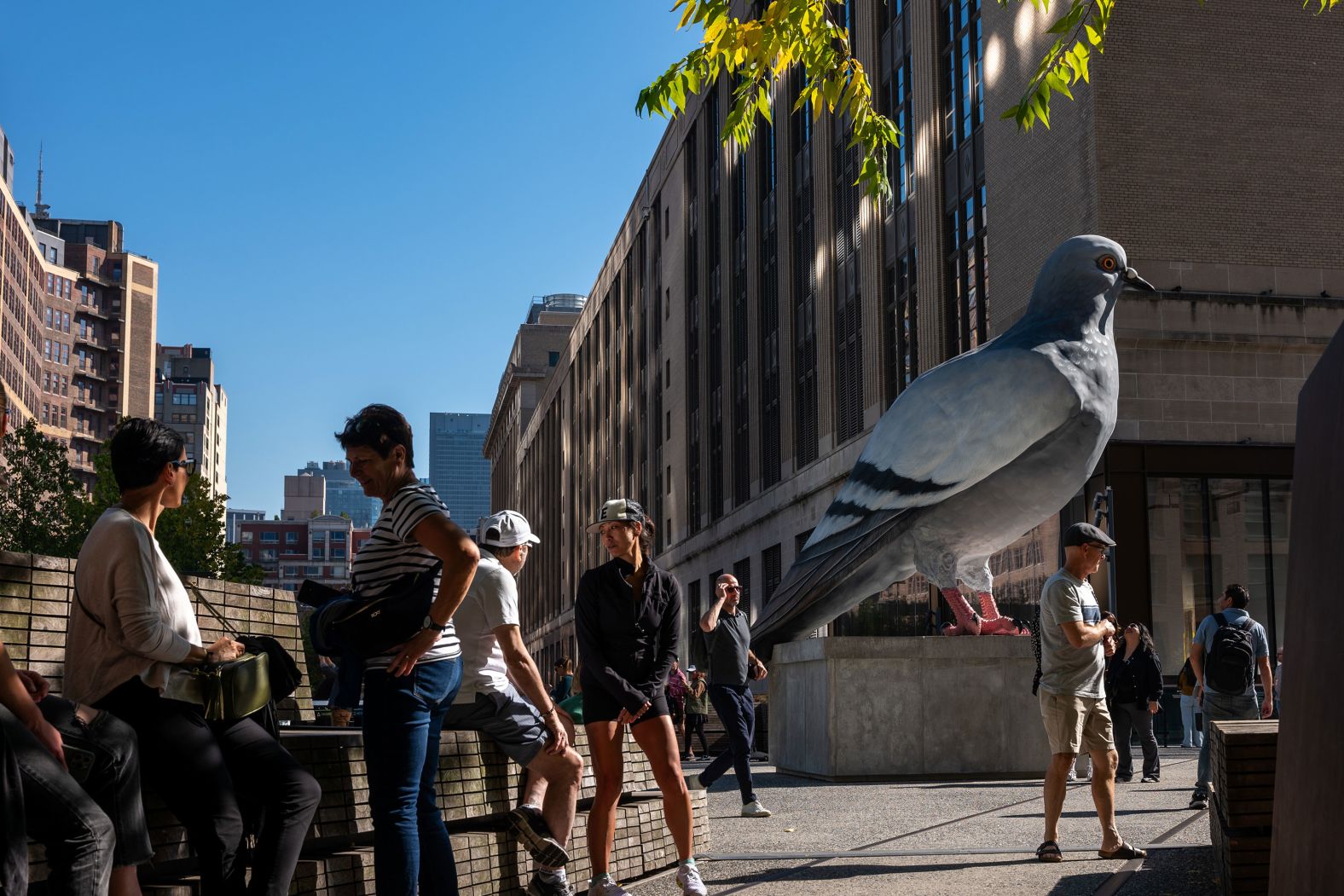 People admire “Dinosaur,” a pigeon sculpture along the High Line in New York, on Monday, October 21. The hand-painted sculpture by artist Iván Argote celebrates the pigeon's distant past as the birds descended from dinosaurs.