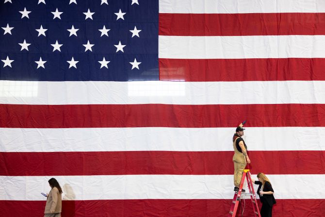 Staff members steam wrinkles out of the US flag that was being used as a backdrop for former President Barack Obama, who would be campaigning for Harris in Pittsburgh on October 10.