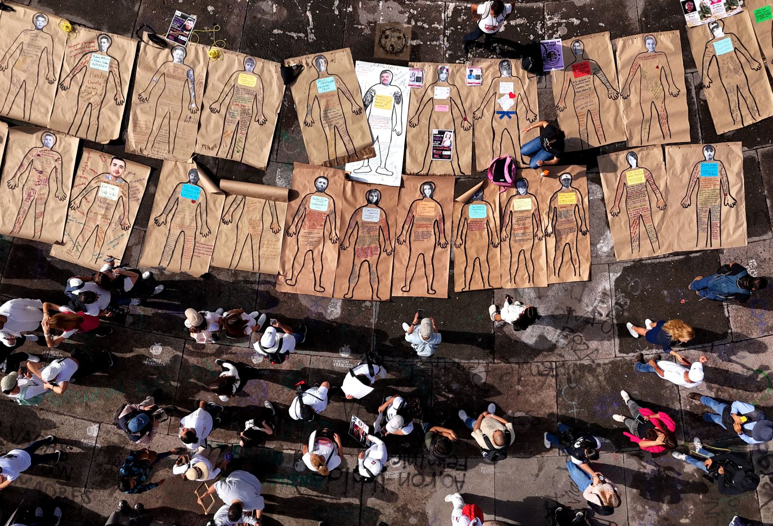 Relatives of missing people place portraits of their loved ones on drawings of human silhouettes during a march on International Day of Victims of Enforced Disappearances in Guadalajara, Mexico, on Friday, August 30.