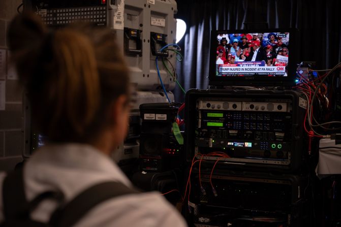 A media member at the Fiserv Forum in Milwaukee watches a news report of the Trump incident.