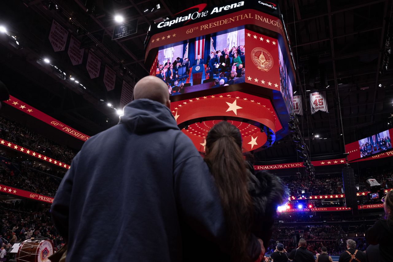 People watch President Donald Trump deliver his inaugural address on a screen in Capital One Arena in Washington, DC on Monday.