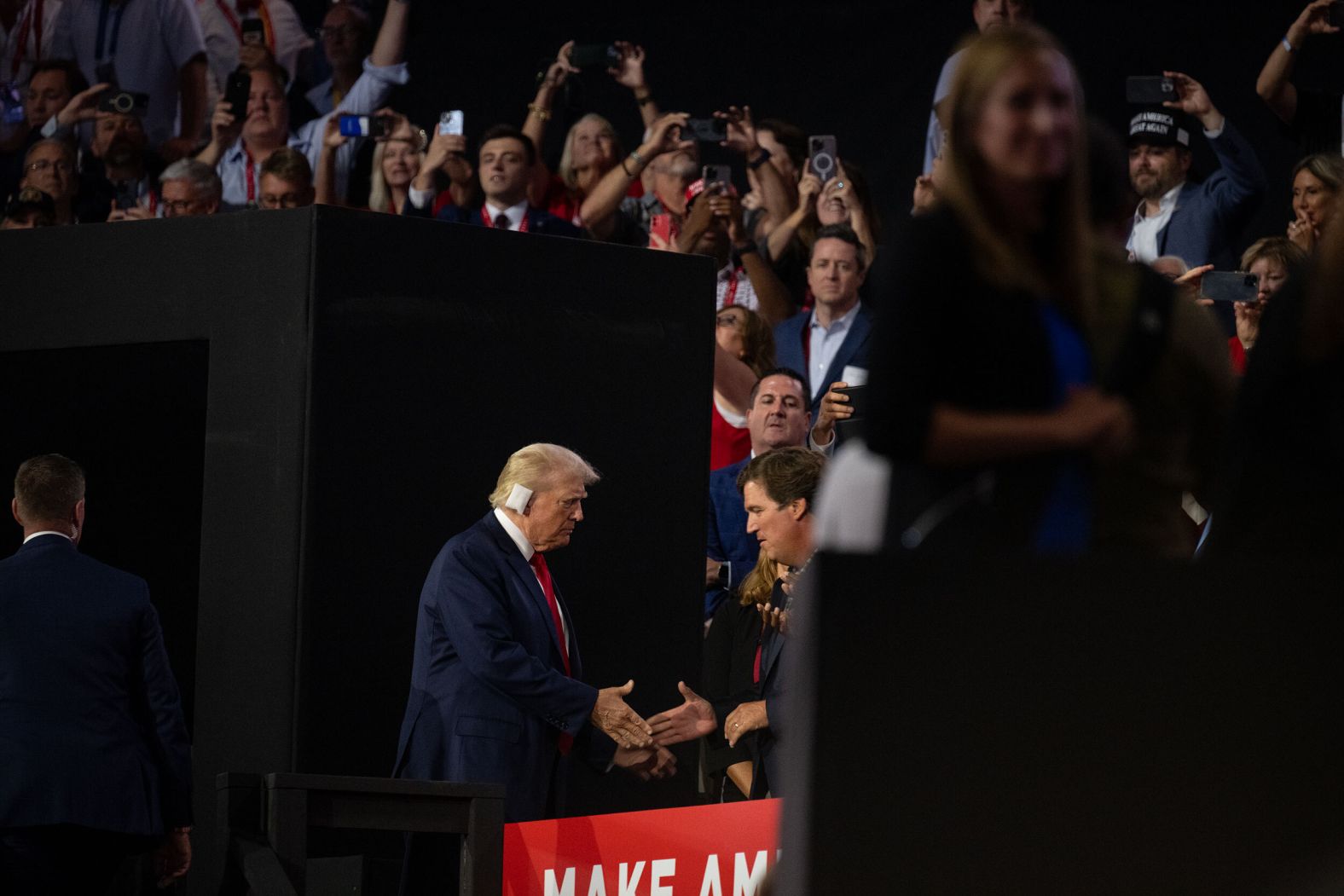 Trump greets former Fox News host Tucker Carlson as he walks onto the convention floor Monday.