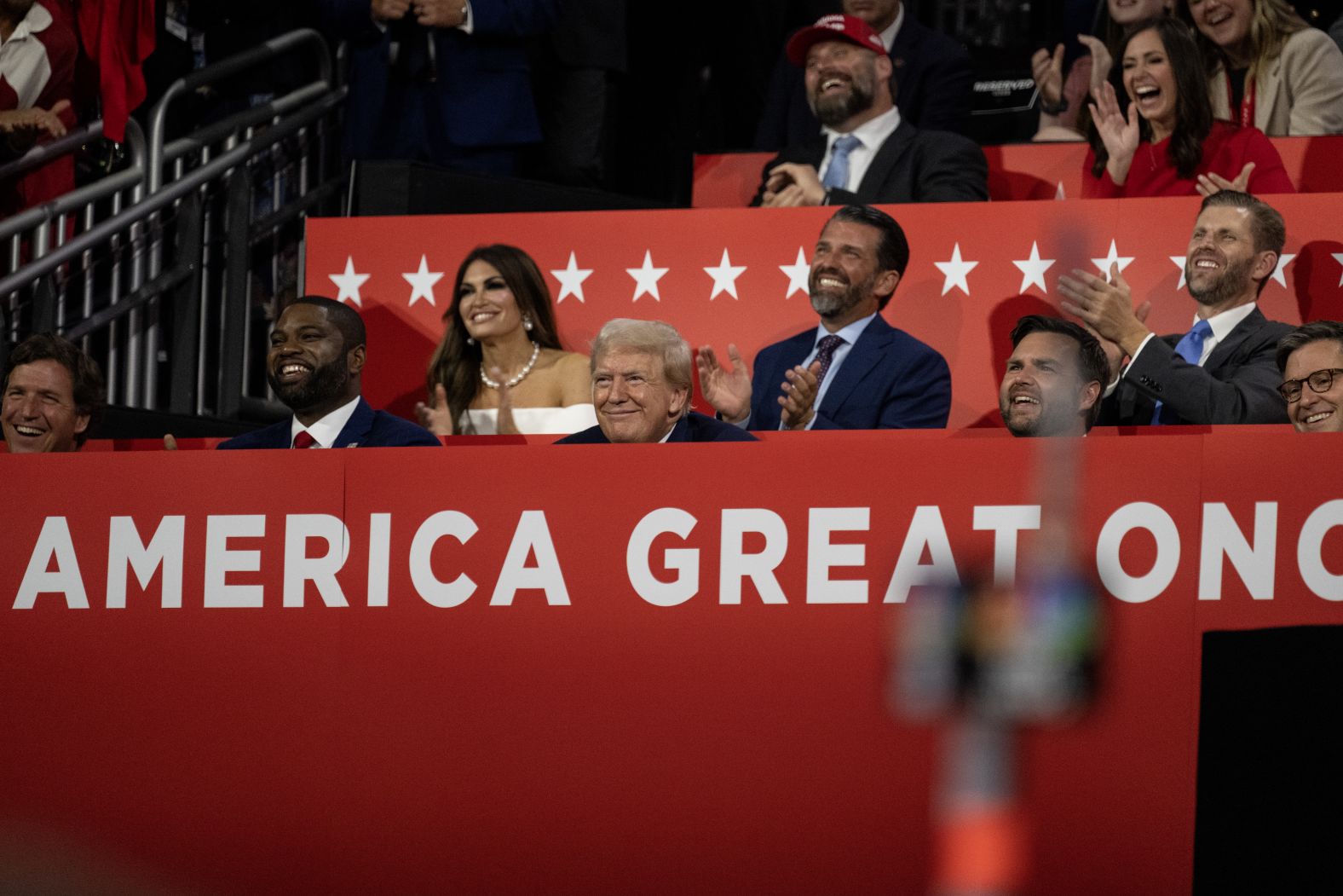 From left, Carlson, US Rep. Byron Donalds, Kimberly Guilfoyle, Trump, Donald Trump Jr., Vance and Eric Trump laugh at a joke during the convention on Monday.