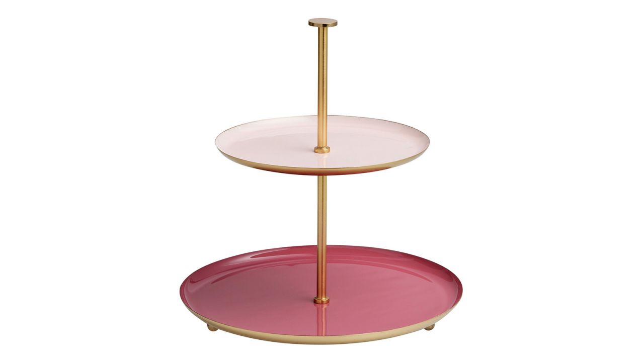 A two-tier serving stand with pink plates centered around a gold rod.
