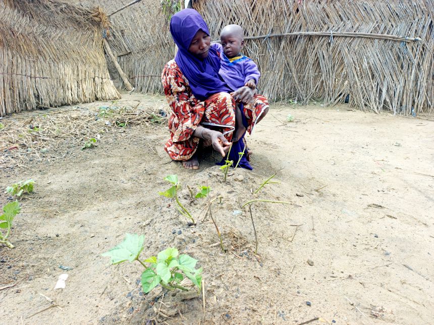Yagana Usman gestures toward her infant twin's grave while holding her surviving son in her arms at the Fulatari camp for internally displaced persons in Borno, northeastern Nigeria, on Sept. 5, 2025.
