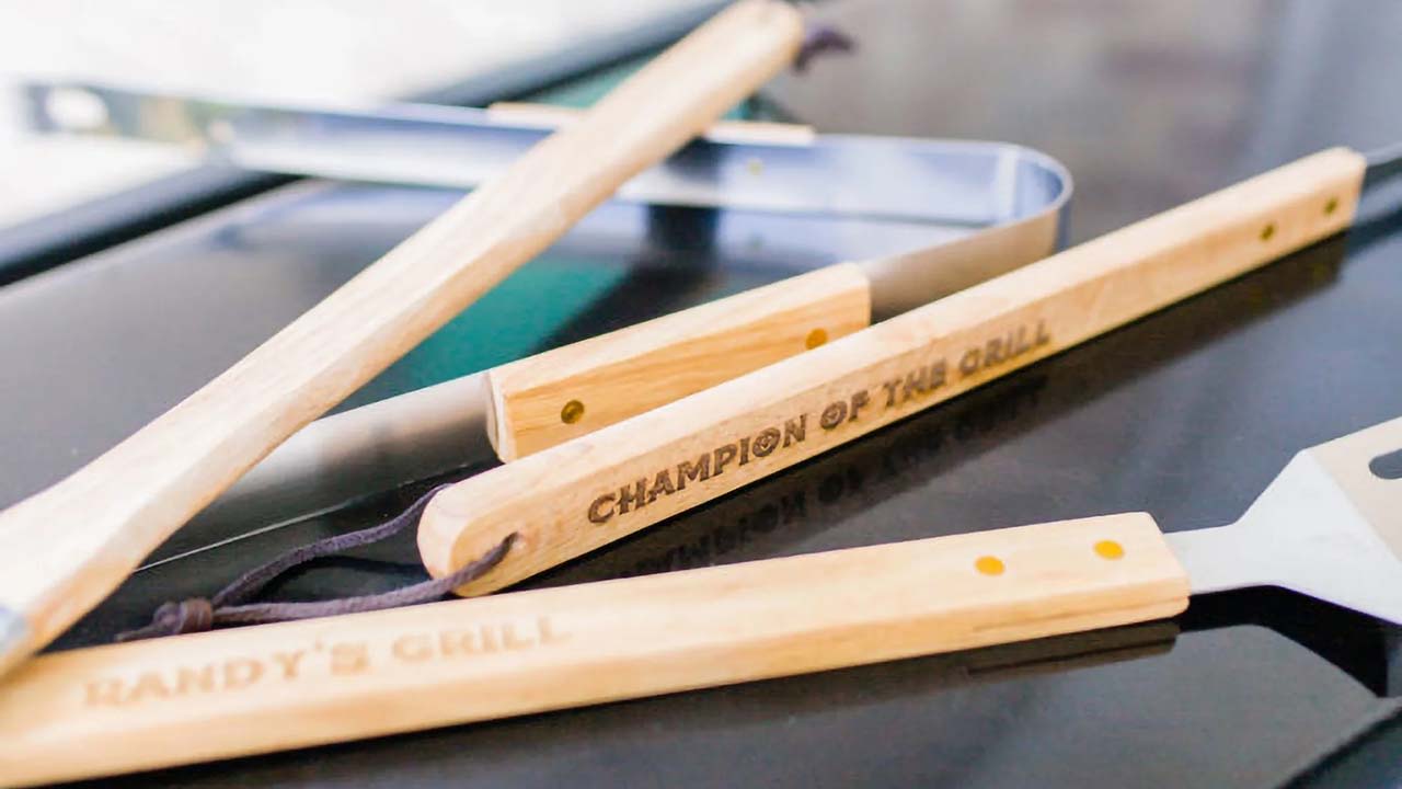 Wooden grill utensils sit on a grill.