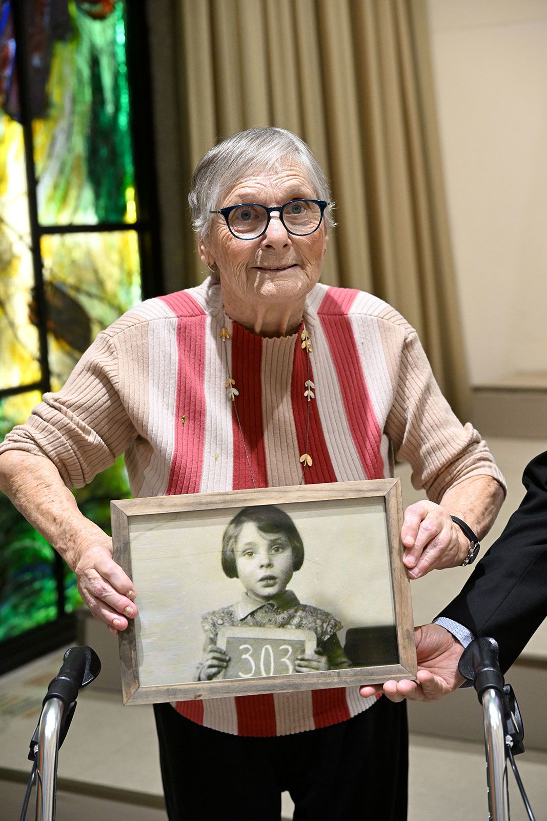 Holocaust and October 7 survivor Mirjam Beit Talmi Szpiro holding a photo of herself as a 3-year-old in Amsterdam, 1939, on the way to Britain.