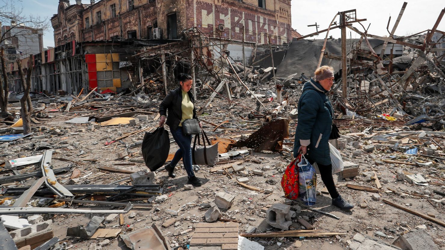 Residents carry their belongings through a destroyed street as fighting rages in Mariupol in April 2022.