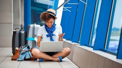 woman sitting on airport terminal floor with laptop